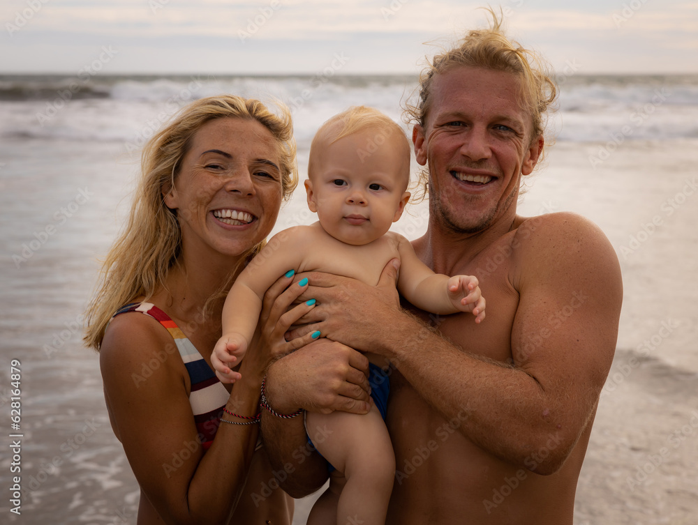 Close up portrait of happy family spending time on the beach. Father and mother holding infant baby boy. Positive emotions. Summer vacation in Asia. Family beach concept. Bali Close up portrait of happy family spending time on the beach. Father and mother holding infant baby boy. Positive emotions. Summer vacation in Asia. Family beach concept. Bali