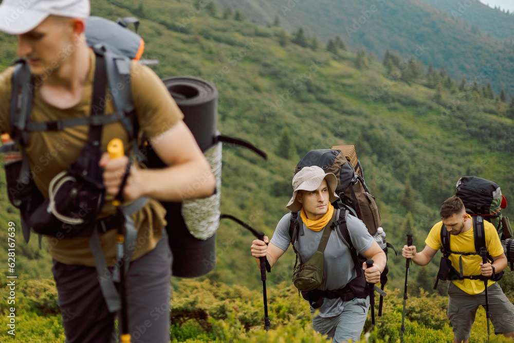 group of 3 hikers climbing the foot of the mountain to its peak, selective focus