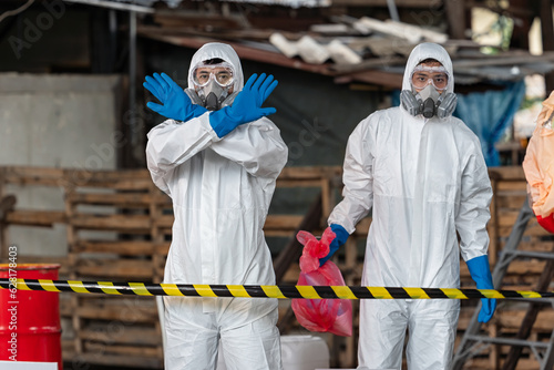 Obraz na płótnie A team of two chemists, wearing PPE suits and gas masks, recover a deadly chemical spill on the factory warehouse floor