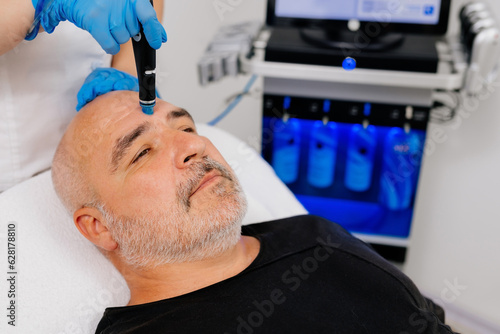 Middle aged male client during deep facial cleansing in a cosmetology clinic photo