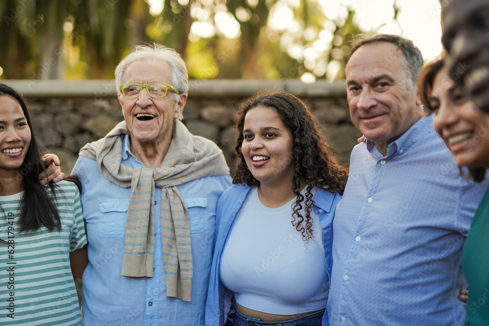 Naklejka premium Group of multi generational people hugging each other outdoor - Multiracial friendship and community concept