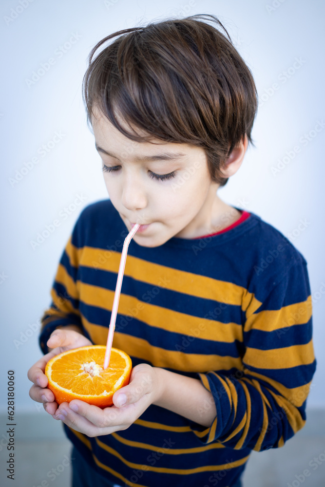 Little cute boy taking juice out of orange Little cute boy taking juice out of orange