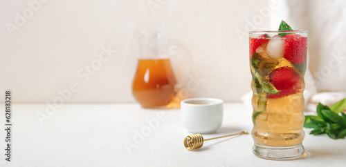 Glass of ice tea with strawberry and mint on white table. Banner for design