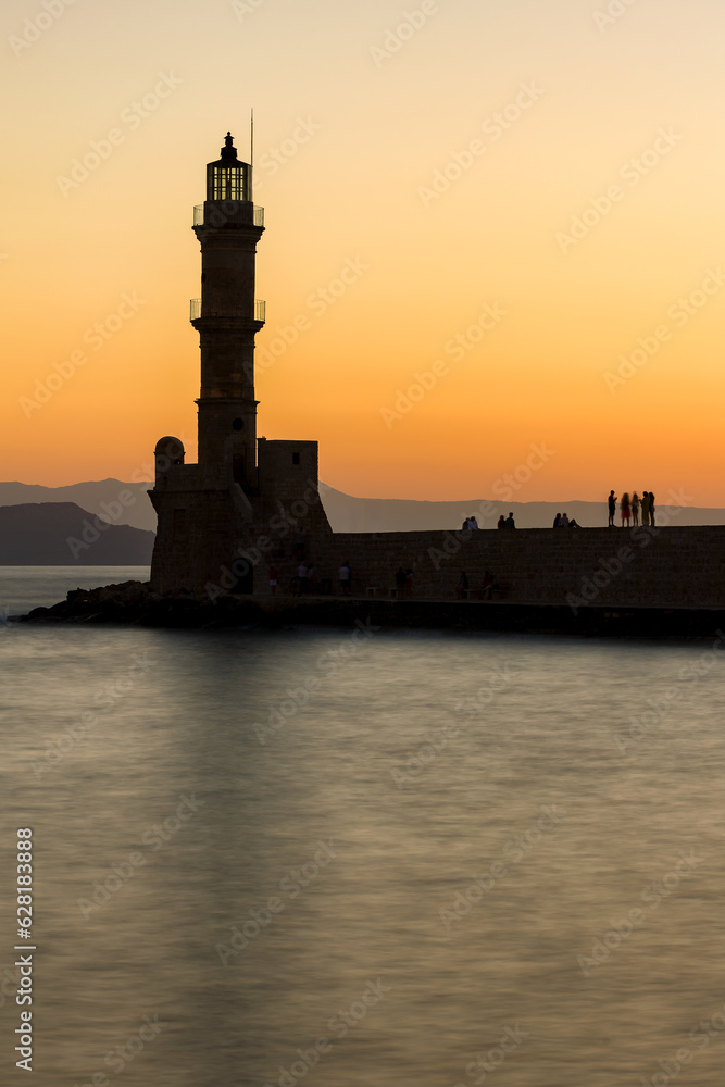 Long exposure, blured image of the old Venetian lighthouse and harbour wall at sunset (Chania, Crete, Greece)