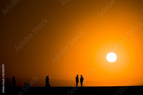 Silhouette of tourists watching a spectacular sunset from a harbour wall (Chania, Crete, Greece)