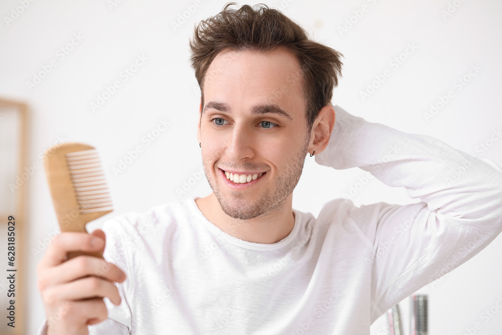 Young man with hair comb in bathroom, closeup Young man with hair comb in bathroom, closeup