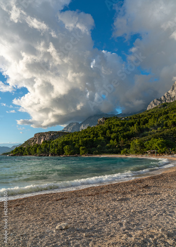 Beautiful seascape. The coastline is covered with rocks, dense forest. Waves on the sea. Sky with huge clouds. Croatia.