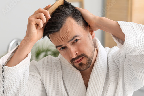 Worried young man combing h...