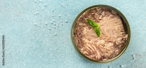 Canned tuna fillet meat in olive oil on a blue background. Long banner format. top view