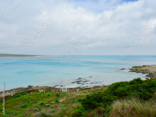 Cloudy sky over picturesque beach of Stintino  on north part of Sardinia  Italy. Shoreline with turquoise water on La Pelosa beach out of season