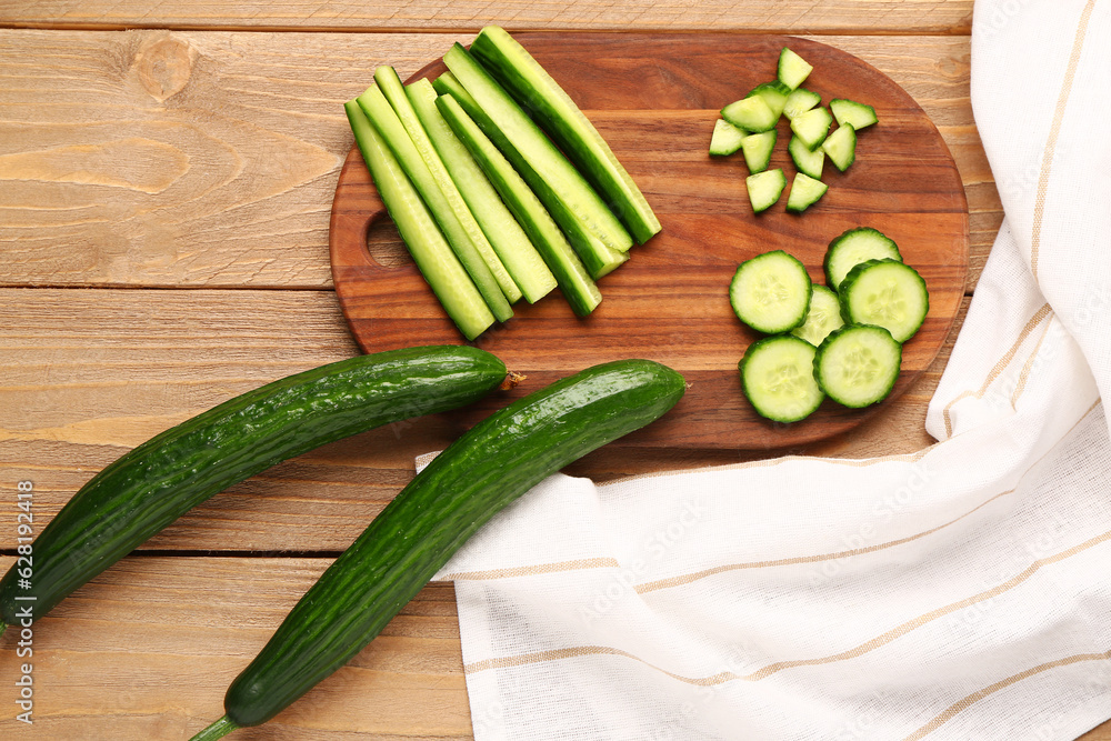Board with cut and whole cucumbers on wooden background Board with cut and whole cucumbers on wooden background