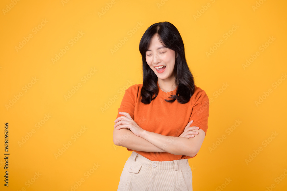 Young asian woman 30s wearing orange shirt showing crossed arm sign gesture isolated on yellow background. Confident female person with hands gesture concept. Young asian woman 30s wearing orange shirt showing crossed arm sign gesture isolated on yellow background. Confident female person with hands gesture concept.