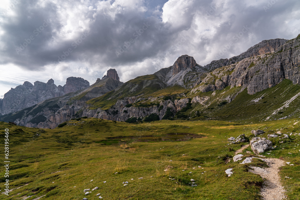 Stunning mountain views. Picturesque landscape. The mountains are covered with dense green forest. Tourist trails. Dark clouds. Beautiful mountain landscape. Dolomites. Italy.