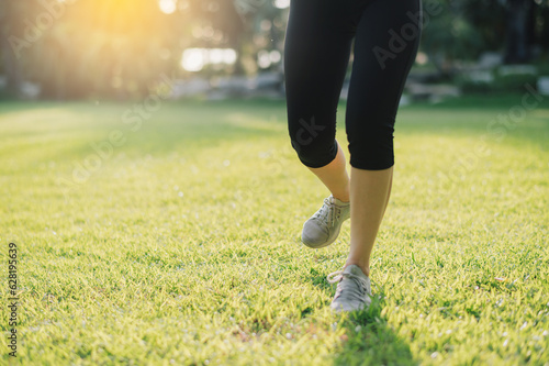 Experience the beauty of a close-up shot of a female jogger's legs and shoes while running at sunset in a public park. Embrace the wellness living concept.