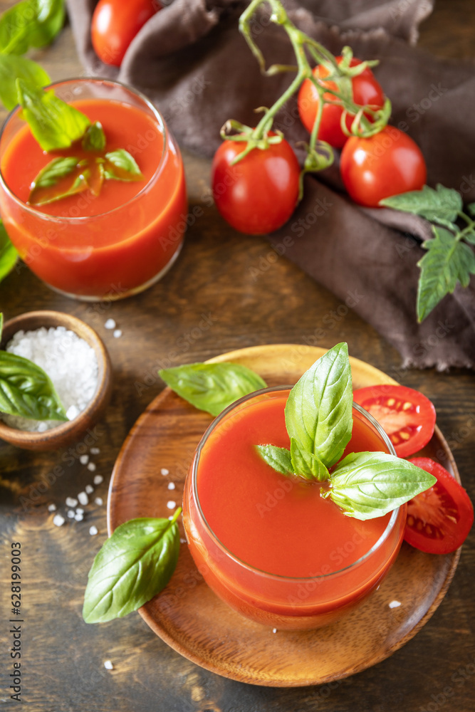 Glasses of fresh tomato juice with tomatoes, salt on wooden table. Vegetable tomato drink for a healthy diet. Glasses of fresh tomato juice with tomatoes, salt on wooden table. Vegetable tomato drink for a healthy diet.