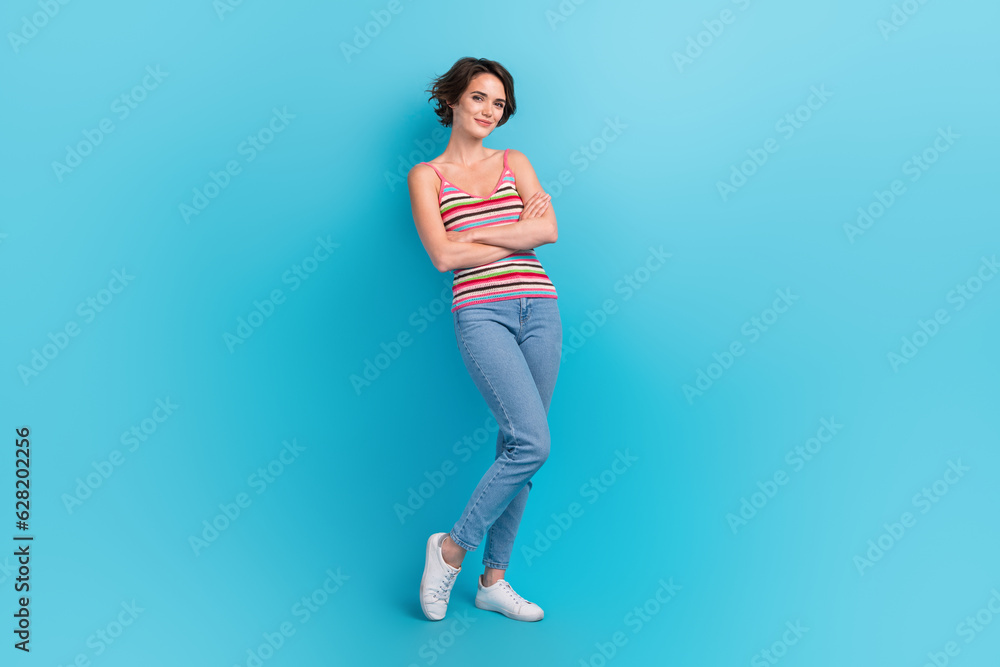 Full size portrait of positive satisfied confident girl crossed arms posing isolated on blue color background Full size portrait of positive satisfied confident girl crossed arms posing isolated on blue color background