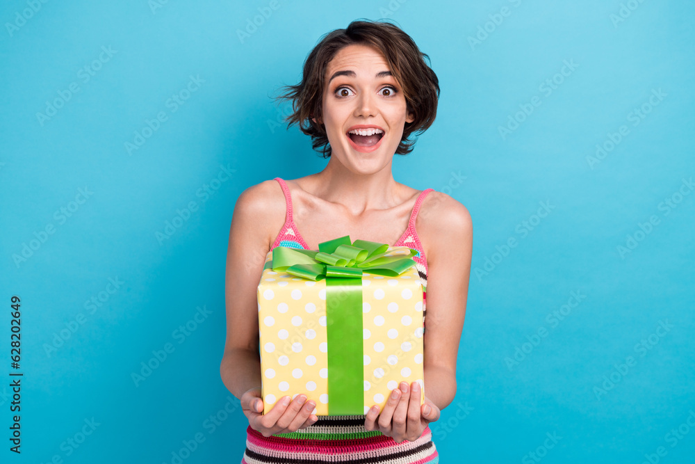 Portrait of impressed cheerful girl open mouth arms hold desirable unexpected giftbox isolated on blue color background Portrait of impressed cheerful girl open mouth arms hold desirable unexpected giftbox isolated on blue color background