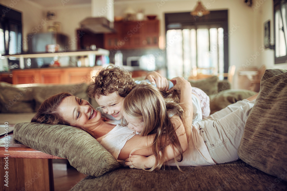 Single mother playing with her son and daughter on the couch in the living room Single mother playing with her son and daughter on the couch in the living room