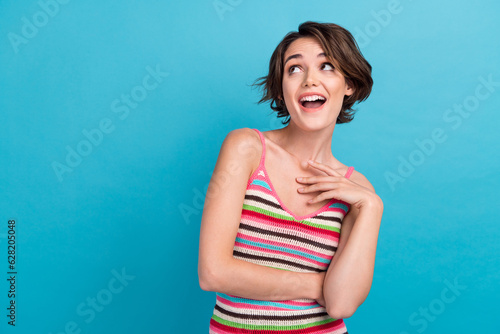 Photo of positive excited lady wear striped singlet looking empty space isolated blue color background