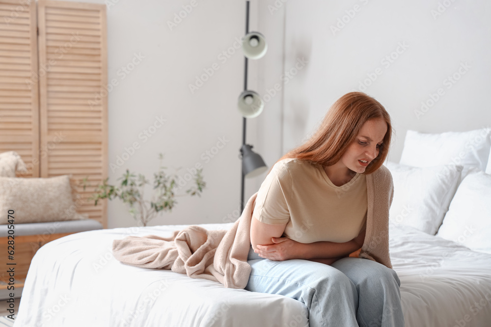 Young woman having menstrual cramps in bedroom Young woman having menstrual cramps in bedroom