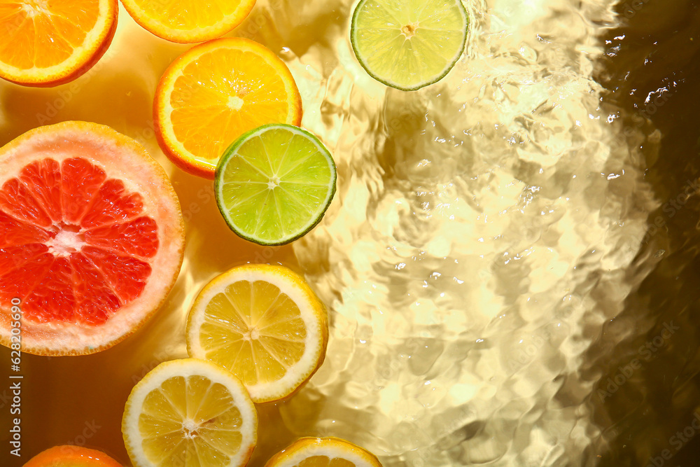 Different citrus fruit slices in water on yellow background Different citrus fruit slices in water on yellow background
