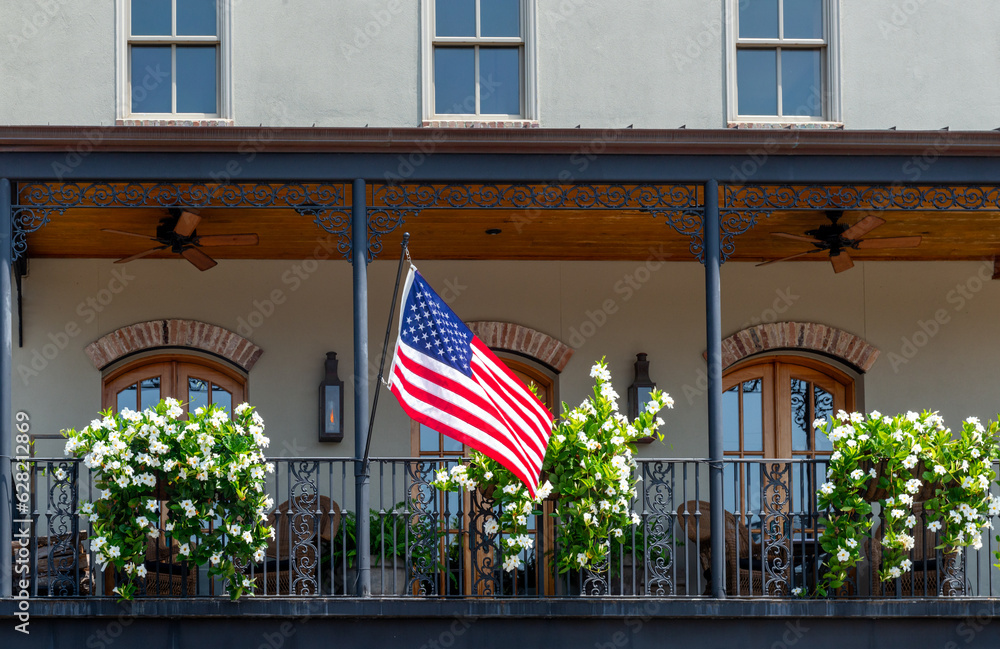 Building with balcony, American flag and mandevilla flowers