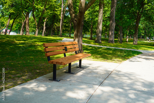Fototapeta Naklejka Na Ścianę i Meble -  Wooden bench in the park, Warm evening in summer park, empty bench for rest.
