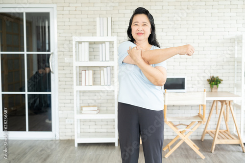 Portrait of senior asian lady bending her arm for warmup before exercise or workout at home, concept of senior people with health conscious