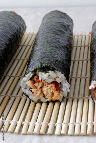 Whole uncut homemade sushi rolls with vegetables and canned tuna fish. photo