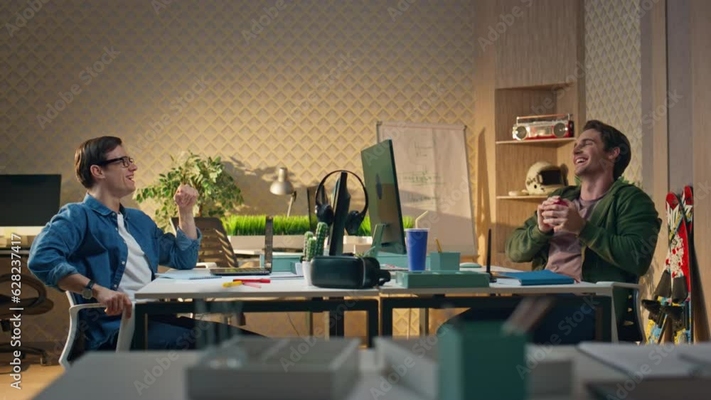Smiling coworkers talking together workplace. Laughing man tossing ball playing Smiling coworkers talking together workplace. Laughing man tossing ball playing