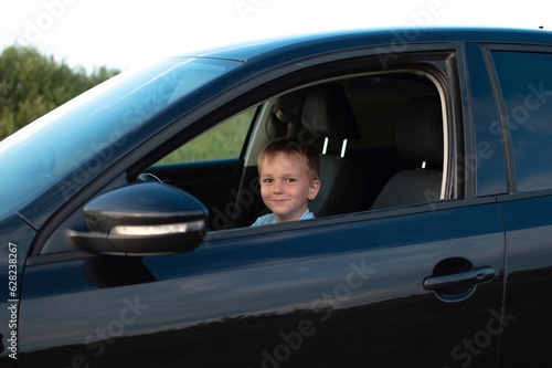 Little boy in the car is happy at the wheel of car holding steering wheel © Inna