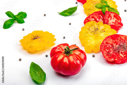 Fototapeta Naklejka Na Ścianę i Meble -  Colorful Heirloom tomato harvest. Ripe ribbed vegetables with fresh basil leaves. Wooden background