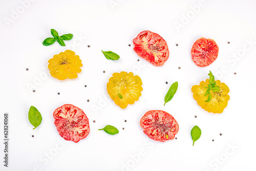 Fototapeta Naklejka Na Ścianę i Meble -  Colorful Heirloom tomato harvest. Ripe ribbed vegetables with fresh basil leaves. Wooden background