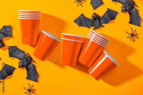 Halloween party background with Paper cup with spiders, bats. Disposable cup made of recycled paper orange colors. Pattern for outumn october holiday all saints day celebration photo