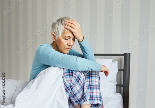 Fototapeta senior bed woman problem pain headache home elderly mature pain bedroom upset un