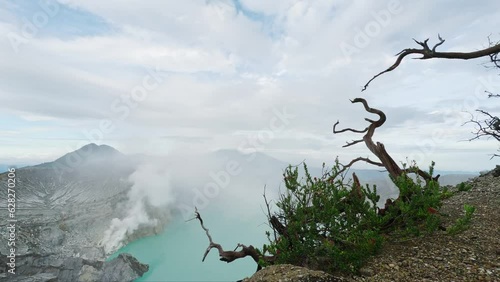 View from mountain of volcano crater landscape with turquoise acid lake and mist over it surrounded volcanic rocks cliffs. Amzing scenery nature in sunny day. Famous travel, tourism destination 4k