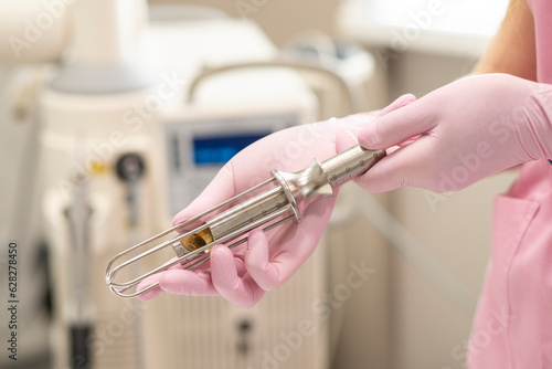 Cuadro en lienzo Close-up of the hands of a female doctor gynecologist in pink medical gloves, holding metal tools, nozzles for Fotona laser gynecology