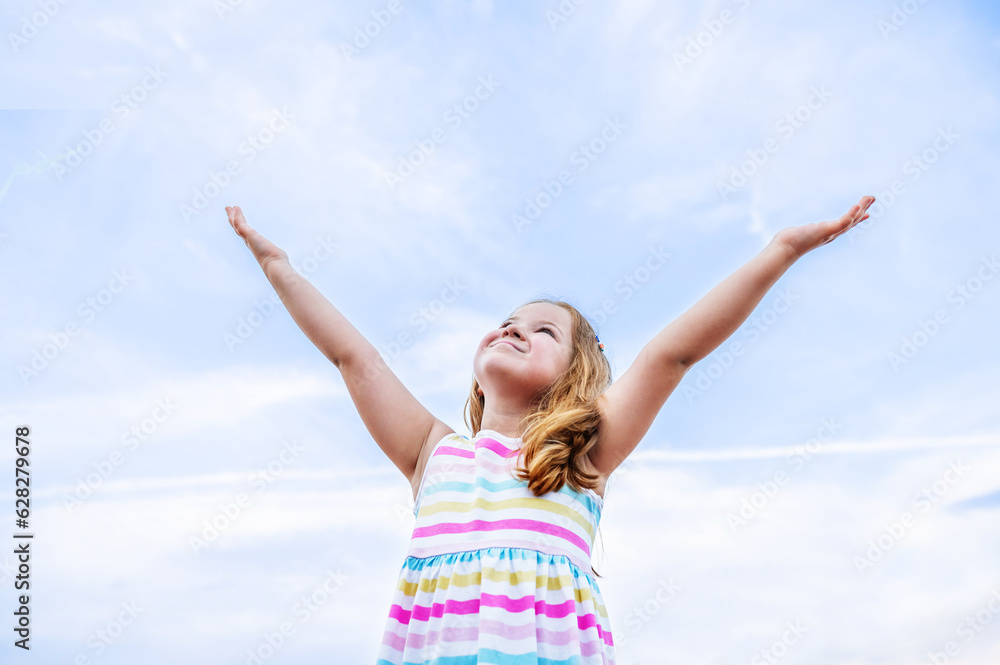 portrait of children, a happy smiling girl of 6 years old, against the background of a clear blue sky.the girl looks at the sky raised her hands up.Place for text. High quality photo portrait of children, a happy smiling girl of 6 years old, against the background of a clear blue sky.the girl looks at the sky raised her hands up.Place for text. High quality photo