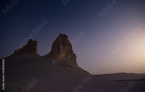 Fototapeta Naklejka Na Ścianę i Meble -  Chalk and limestone remnants in the Kazakh steppe at night against the background of the starry sky and the moon, vertical landforms after weathering in the desert