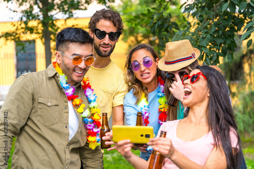 Multi ethnic group of friends partying in the city park taking a selfie, friendship and fun concept wearing sunglasses at a birthday party