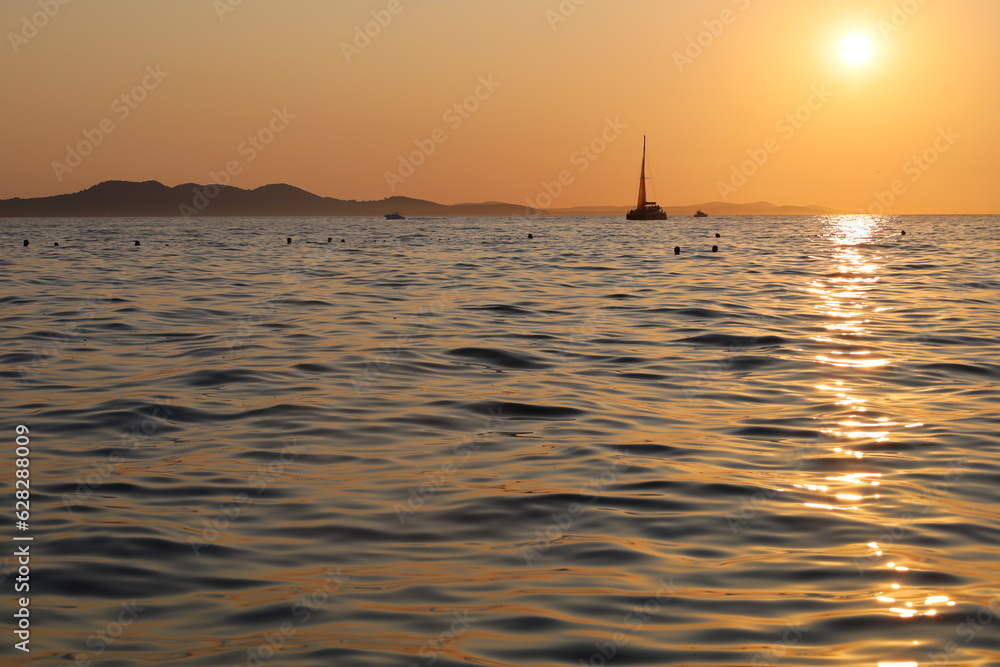 The yacht sails on the sea against the background of the sunset in Zadar in Croatia