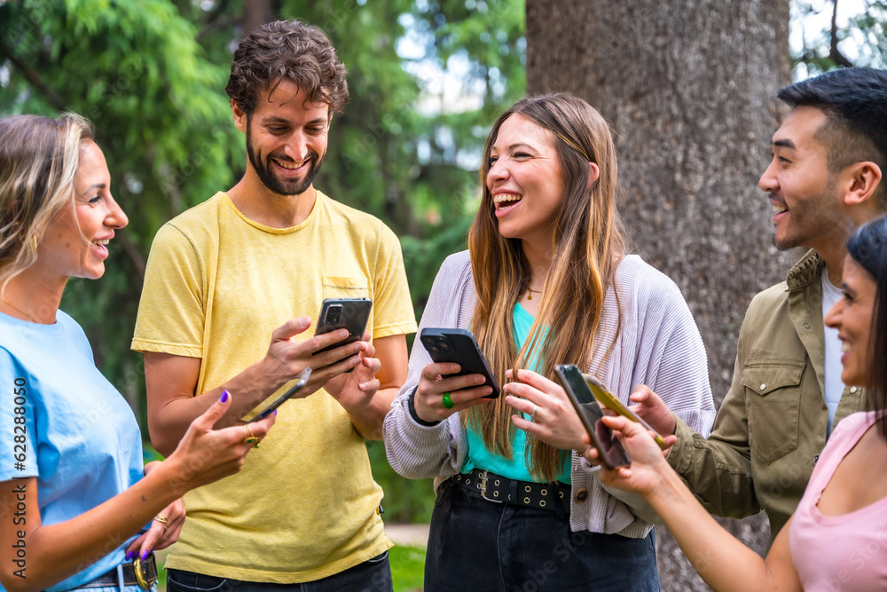 Multiethnic group smiling with phones on internet or social networks in the park, technology concept