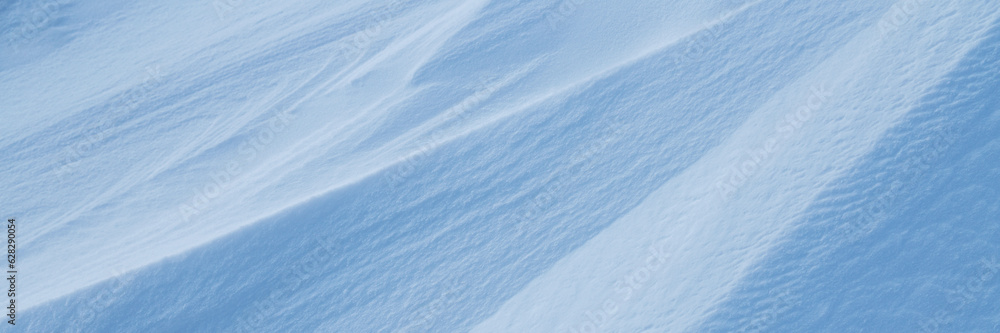 Snow texture. Wind sculpted patterns on snow surface. Wind in the tundra and in the mountains on the surface of the snow sculpts patterns and ridges. Arctic, Polar region. Winter panoramic background. Snow texture. Wind sculpted patterns on snow surface. Wind in the tundra and in the mountains on the surface of the snow sculpts patterns and ridges. Arctic, Polar region. Winter panoramic background.