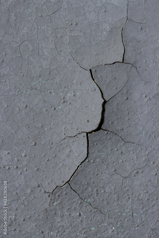 Obraz premium Peeling paint on the wall. Old concrete wall with cracked flaking paint. Weathered rough painted surface with patterns of cracks and peeling. Grunge texture for background and design. High resolution.