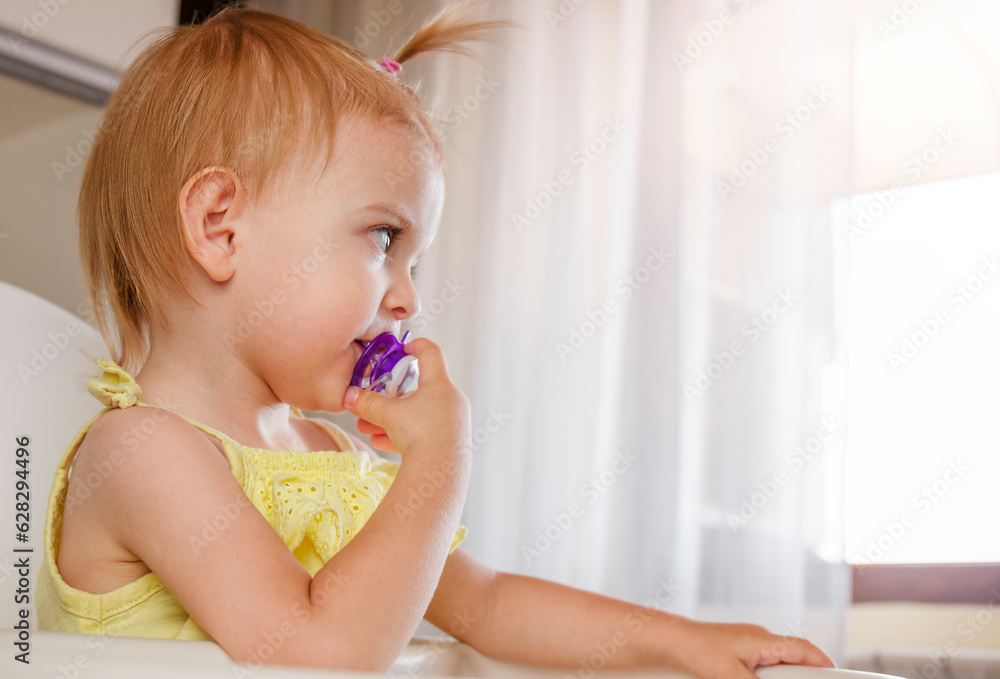 Toddler girl with pacifier sitting on highchair. Copy Space Toddler girl with pacifier sitting on highchair. Copy Space