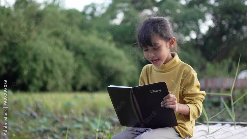 A Little girl reading a diary in the park. A Little girl reading a diary in the park.