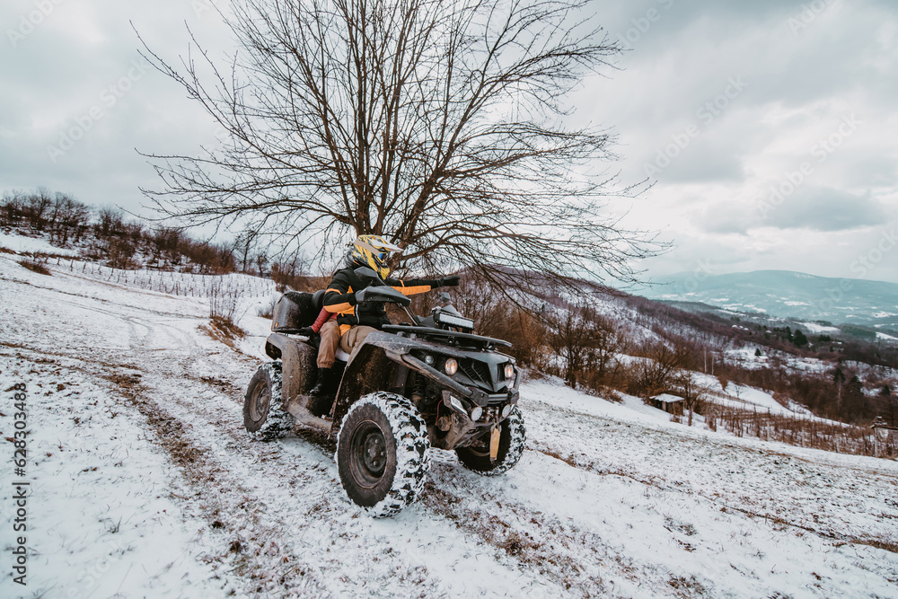 A young adventurous couple embraces the joy of love and thrill as they ride an ATV Quad through the snowy mountainous terrain A young adventurous couple embraces the joy of love and thrill as they ride an ATV Quad through the snowy mountainous terrain