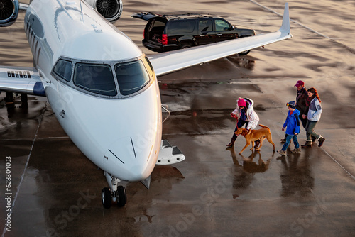 High angle view of Family with dog boarding private plane on wet tarmac of private airport for family vacation 