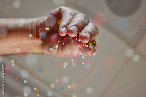Low angle view of baker sprinkling decorative sprinkles by hand on to fresh baked treats  photo