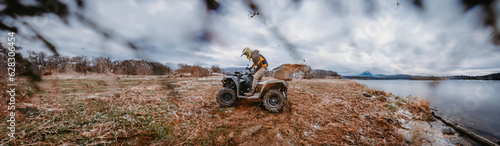 Wide photo of a man is fearlessly enjoying an adventurous ride on an ATV Quad through hazardous snowy terrain, embracing the thrill and excitement of the challenging mountainous landscape